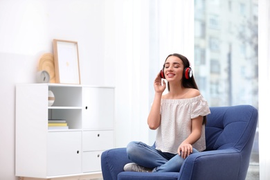 Young woman with headphones resting in armchair at home