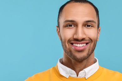 Photo of Smiling man with healthy clean teeth on light blue background. Space for text