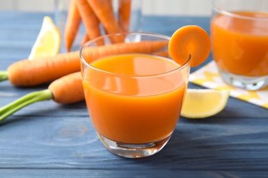 Photo of Glass with fresh carrot juice on wooden table