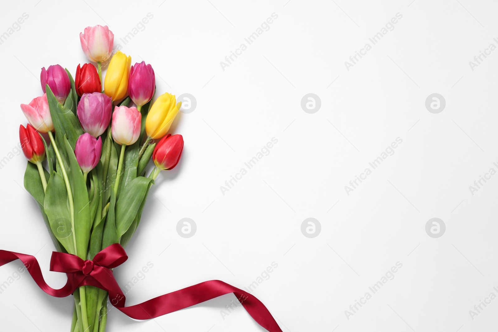 Photo of Beautiful colorful tulip flowers and ribbon on white background, top view. Space for text