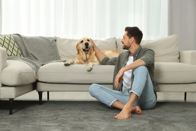 Happy man with his cute Labrador Retriever at home