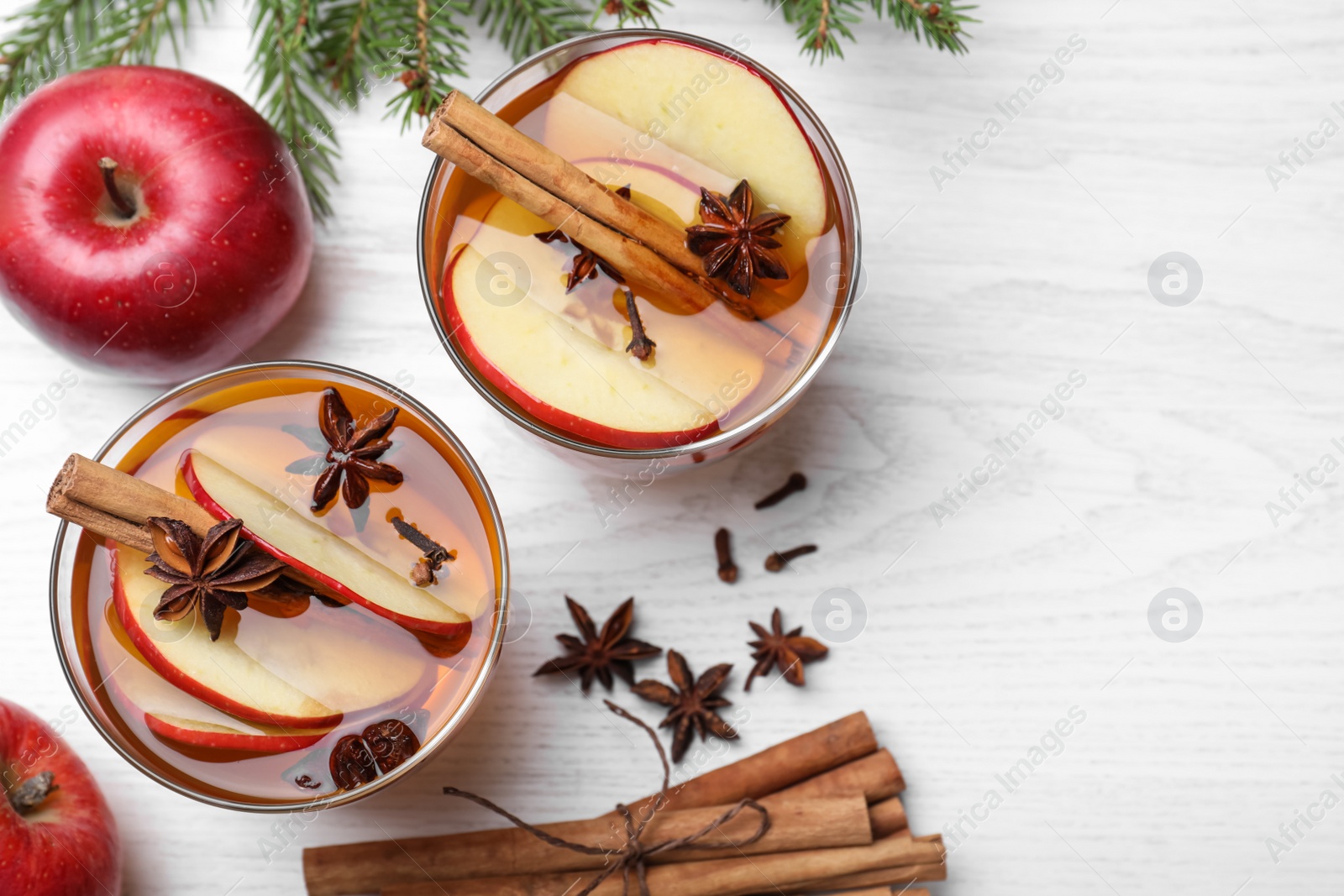 Photo of Hot mulled cider, ingredients and fir branches on white wooden table, flat lay. Space for text