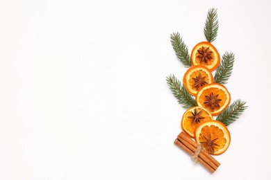Photo of Dry orange slices, cinnamon sticks, fir branches and anise stars on white background, flat lay. Space for text