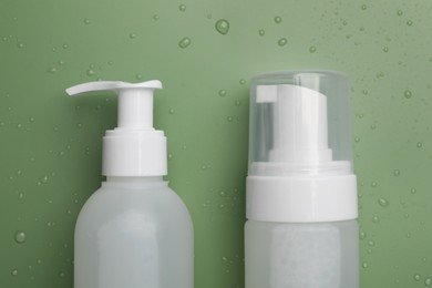 Wet bottles of face cleansing product on green background, flat lay