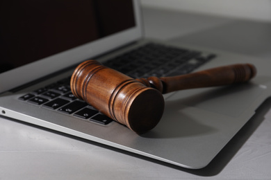 Photo of Laptop and wooden gavel on light table. Cyber crime