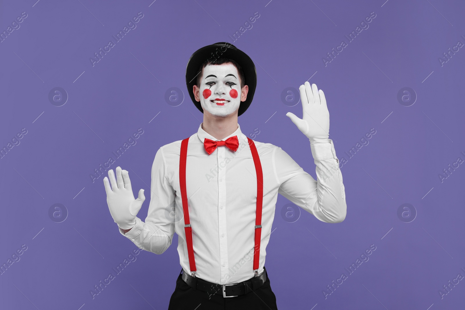 Photo of Funny mime artist in hat posing on purple background