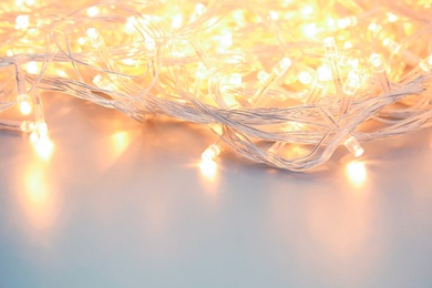 Glowing Christmas lights on table, closeup. Festive illumination