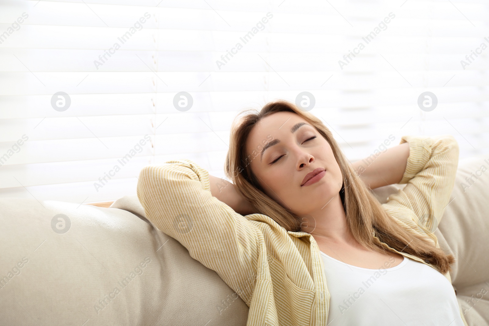 Photo of Beautiful young woman relaxing on sofa indoors