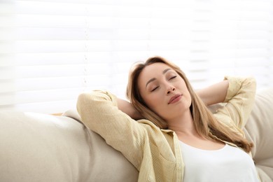 Beautiful young woman relaxing on sofa indoors