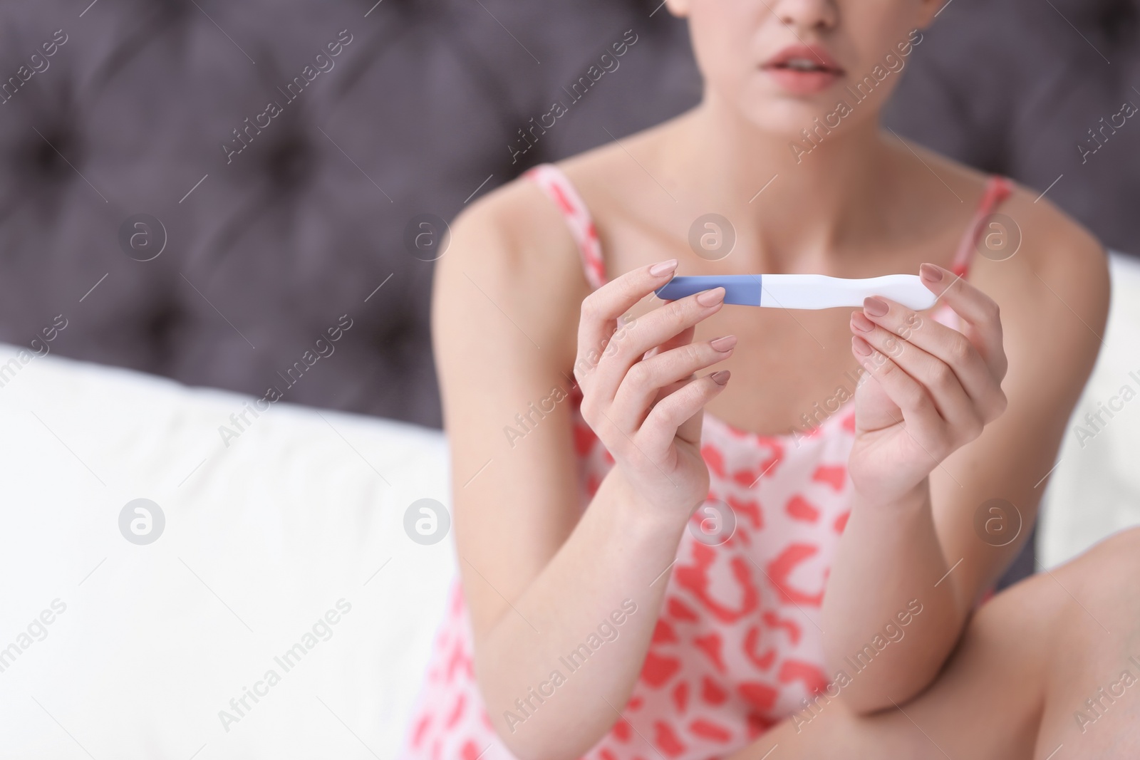 Photo of Young woman with pregnancy test on blurred background, closeup. Gynecology