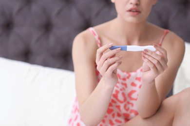 Photo of Young woman with pregnancy test on blurred background, closeup. Gynecology