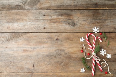 Photo of Flat lay composition with candy canes on wooden background, space for text. Winter holidays