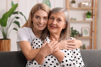 Happy mature mother and her daughter hugging at home