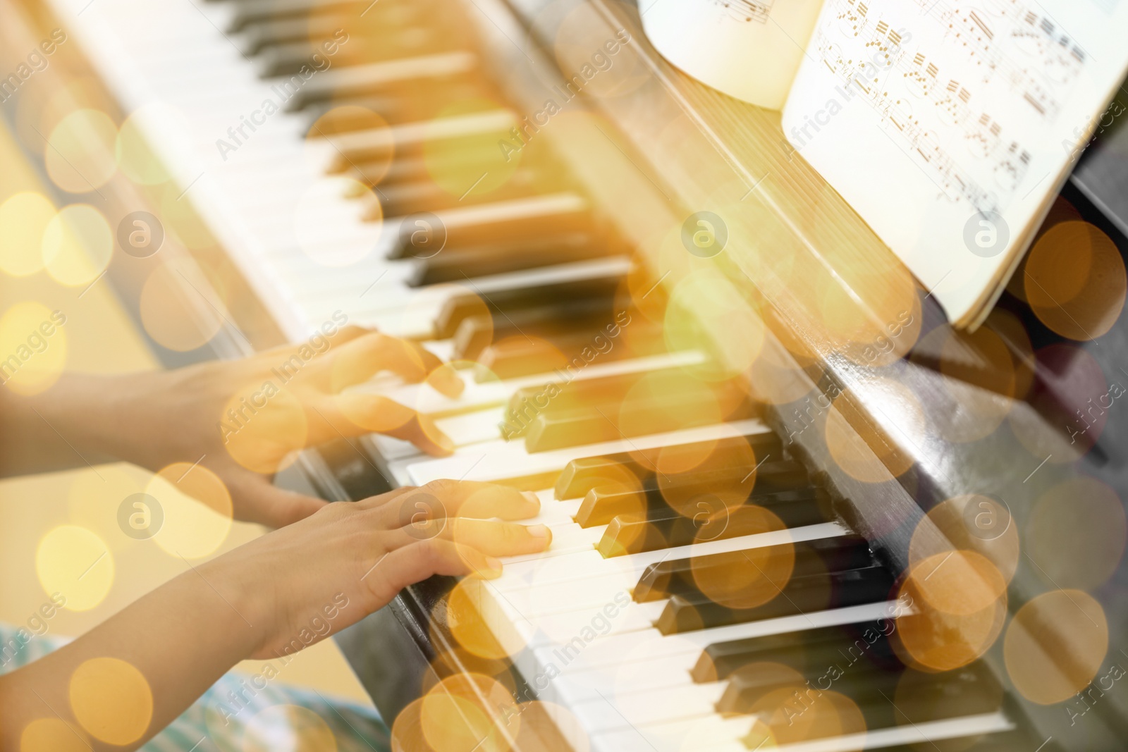 Image of Christmas and New Year music. Little girl playing piano indoors, closeup. Bokeh effect