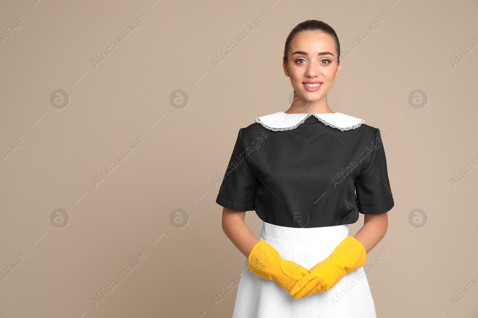 Photo of Portrait of young chambermaid in tidy uniform on color background