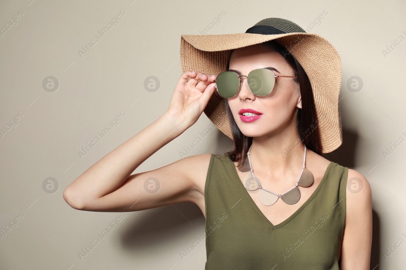 Photo of Beautiful woman in stylish sunglasses and hat on beige background