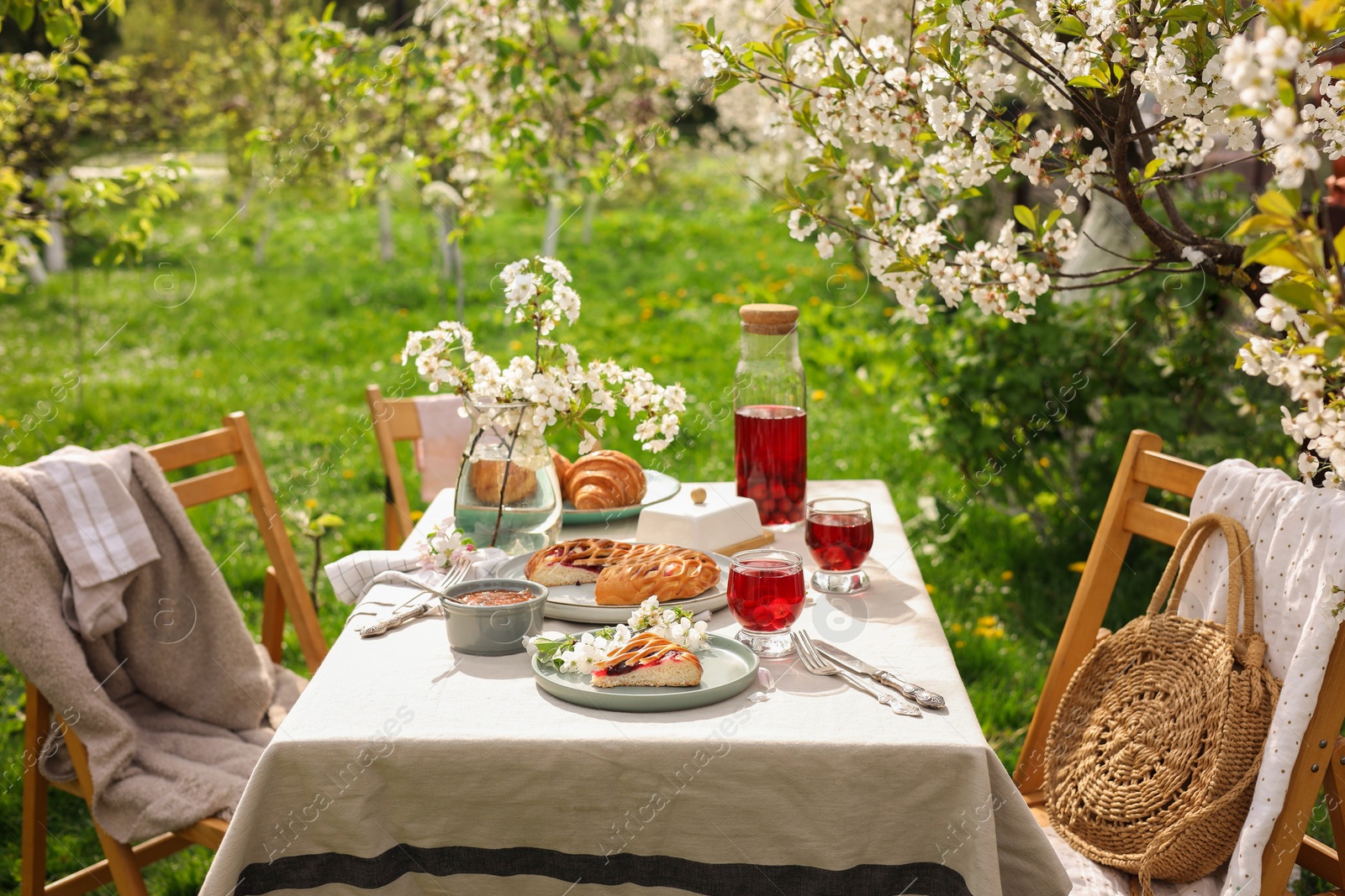 Photo of Stylish table setting with beautiful spring flowers, fruit drink and pie in garden