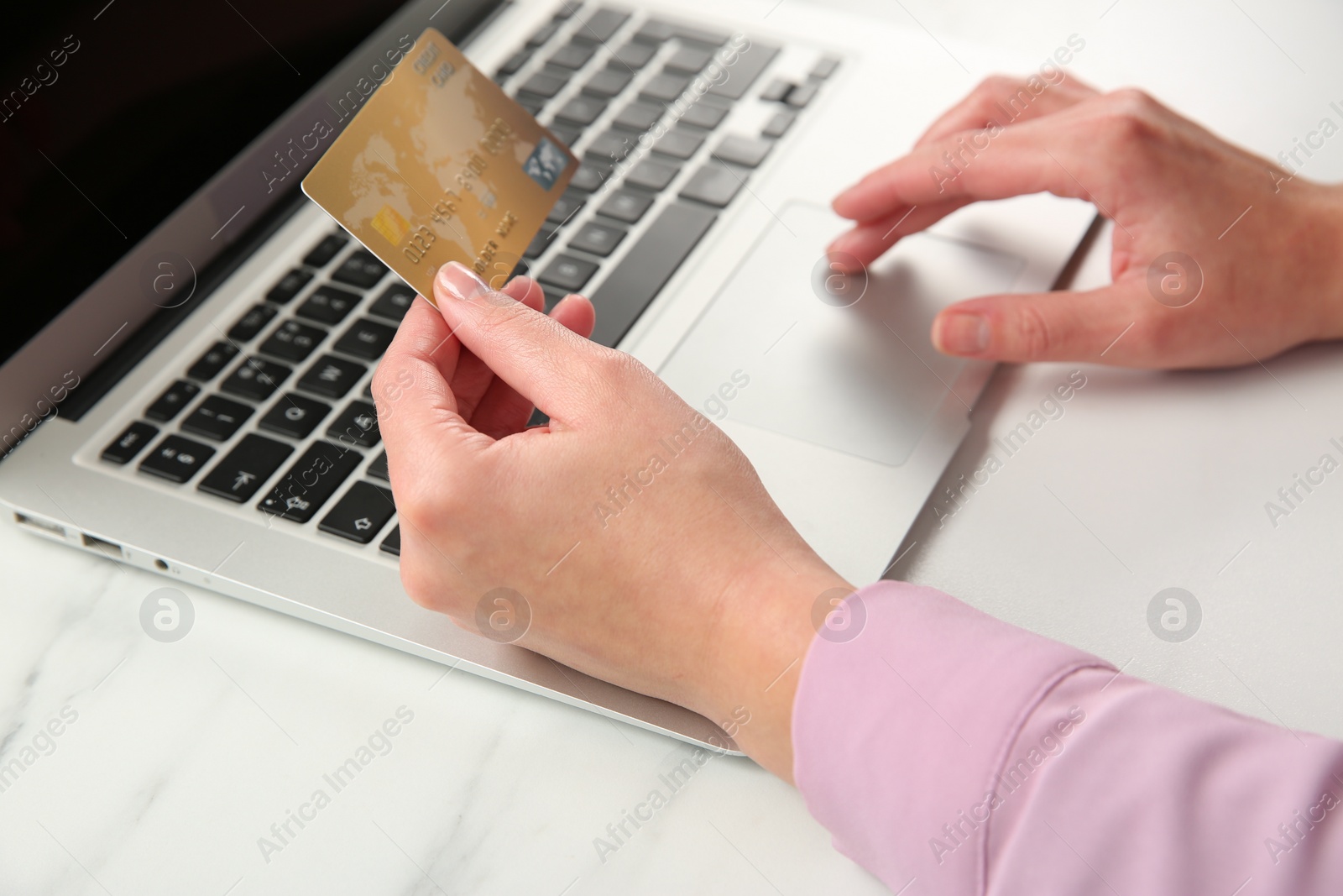 Photo of Online payment. Woman using credit card and laptop at white marble table, closeup