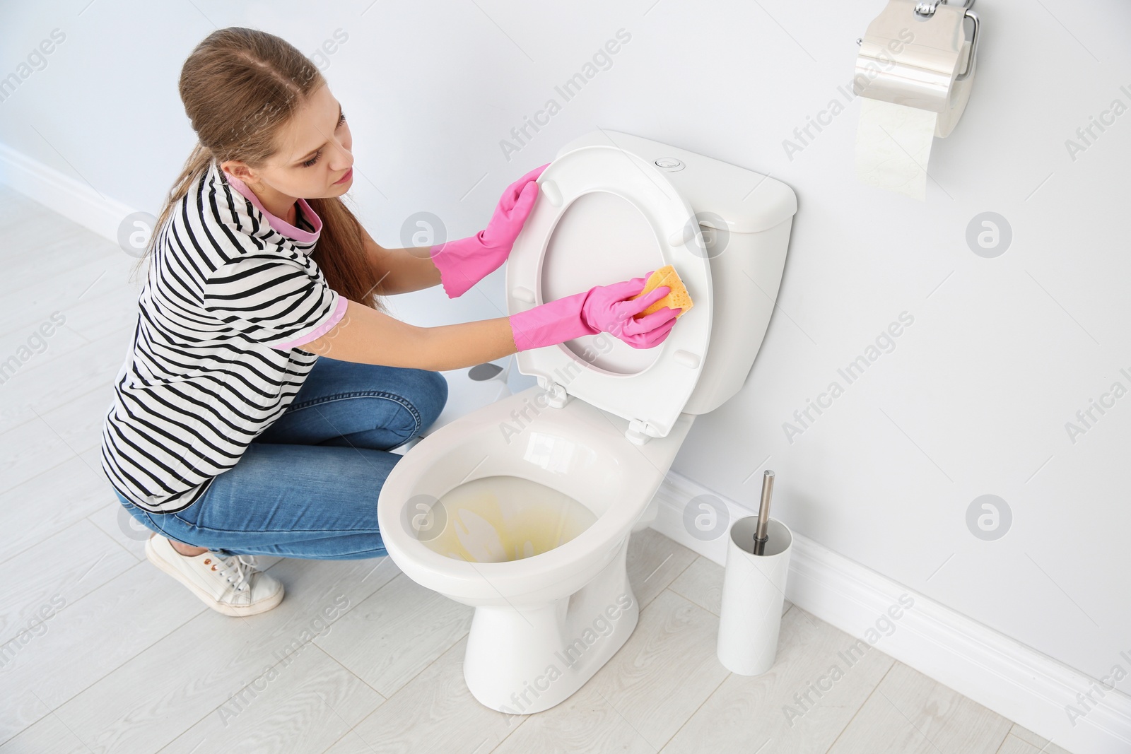 Photo of Woman cleaning toilet bowl in bathroom