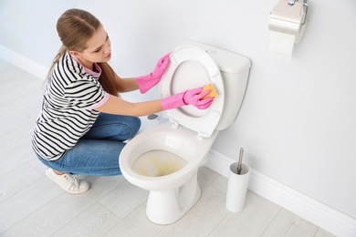 Woman cleaning toilet bowl in bathroom