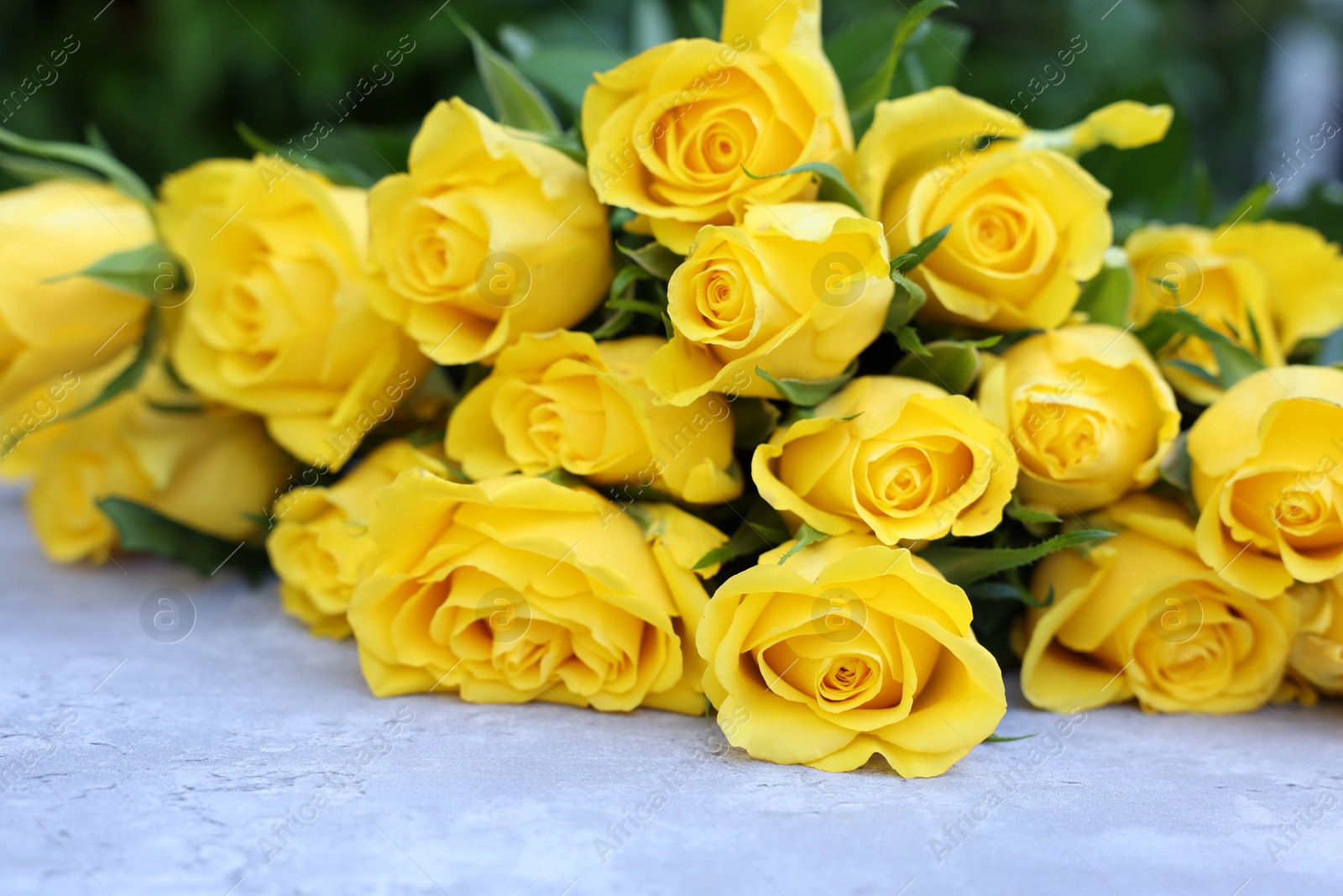 Photo of Beautiful bouquet of yellow roses on light table, closeup