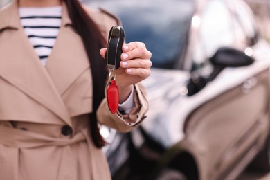 Woman holding car flip key near her vehicle outdoors, closeup