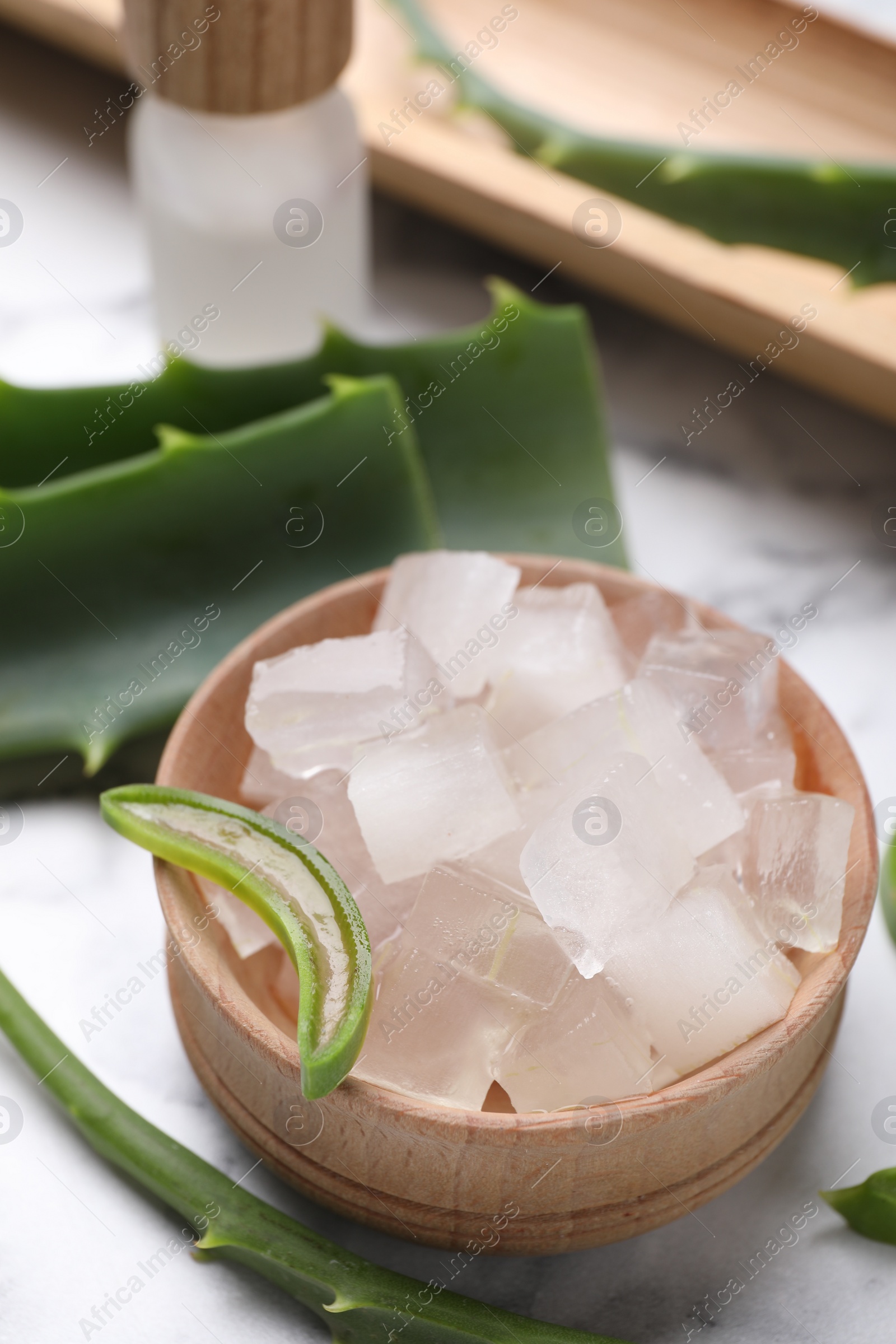 Photo of Aloe vera gel and slices of plant on white table, closeup