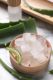 Photo of Aloe vera gel and slices of plant on white table, closeup