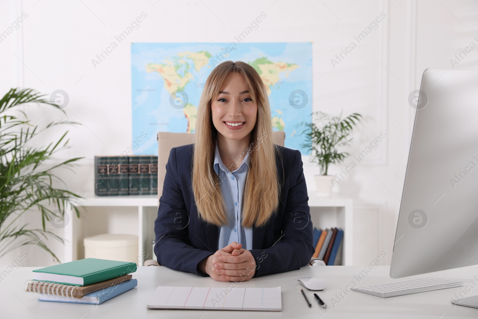 Photo of Happy manager with notebook sitting at desk in travel agency