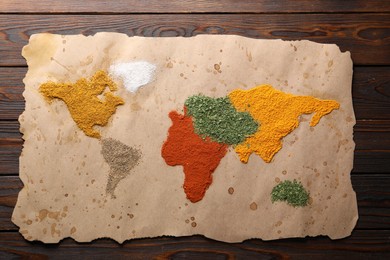 World map of different spices on wooden table, top view