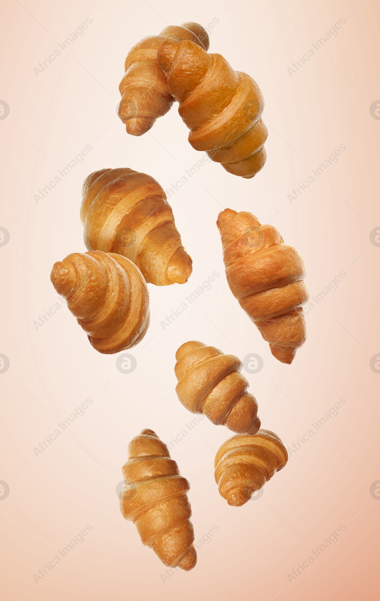 Image of Golden croissants falling on beige gradient background