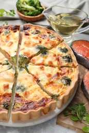 Delicious homemade quiche and ingredients on light gray table