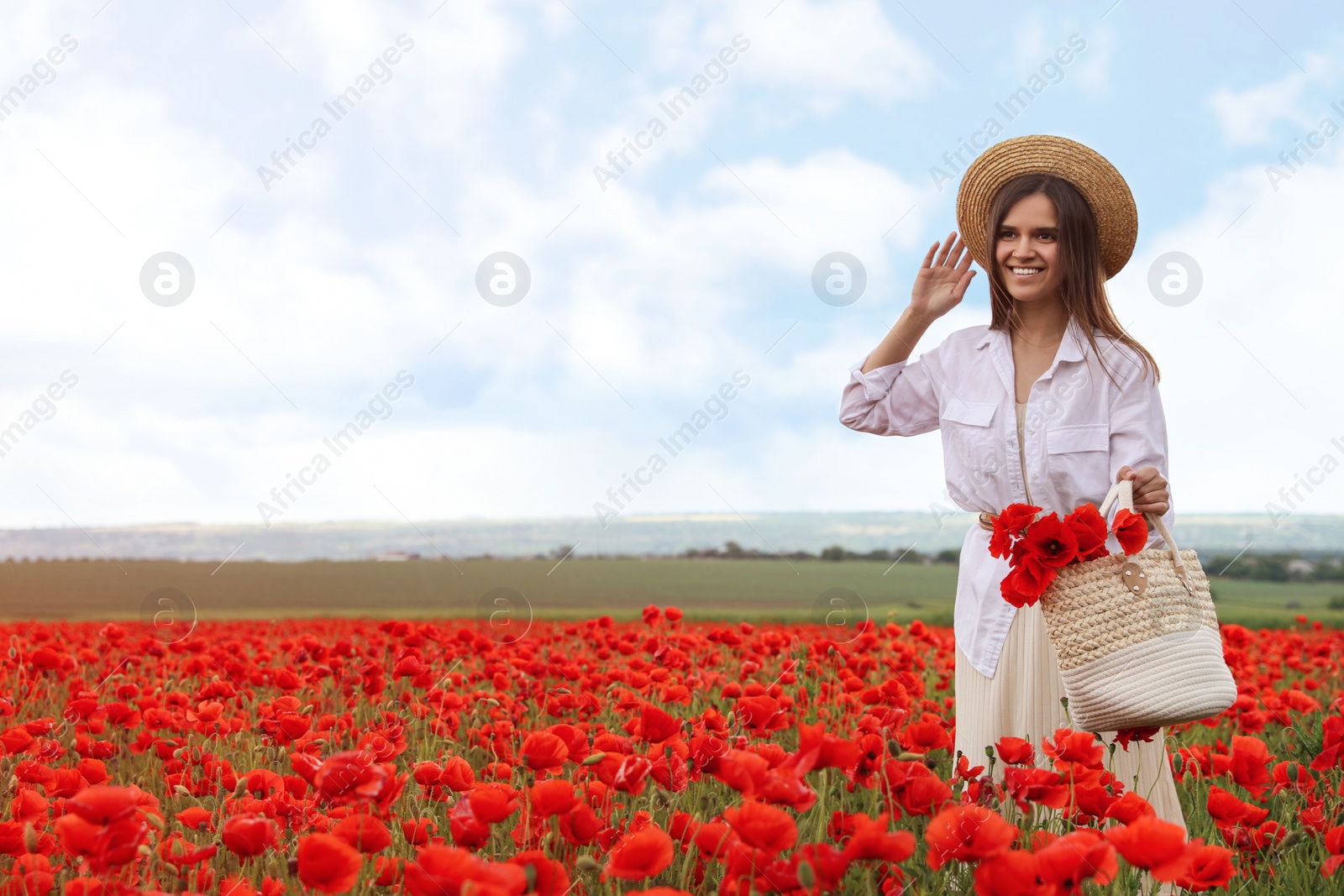 Photo of Woman holding handbag with poppy flowers in beautiful field
