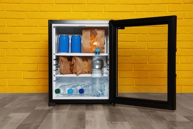 Mini bar filled with food and drinks near yellow brick wall indoors