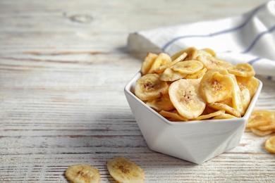 Bowl with sweet banana slices on wooden  table, space for text. Dried fruit as healthy snack