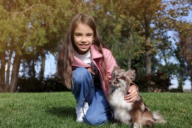 Little girl with her cute dog in park. Autumn walk