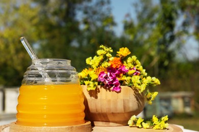 Photo of Delicious fresh honey and beautiful flowers on wooden board in apiary