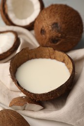 Delicious vegan milk in coconut and pieces of ripe fruit on white table, closeup