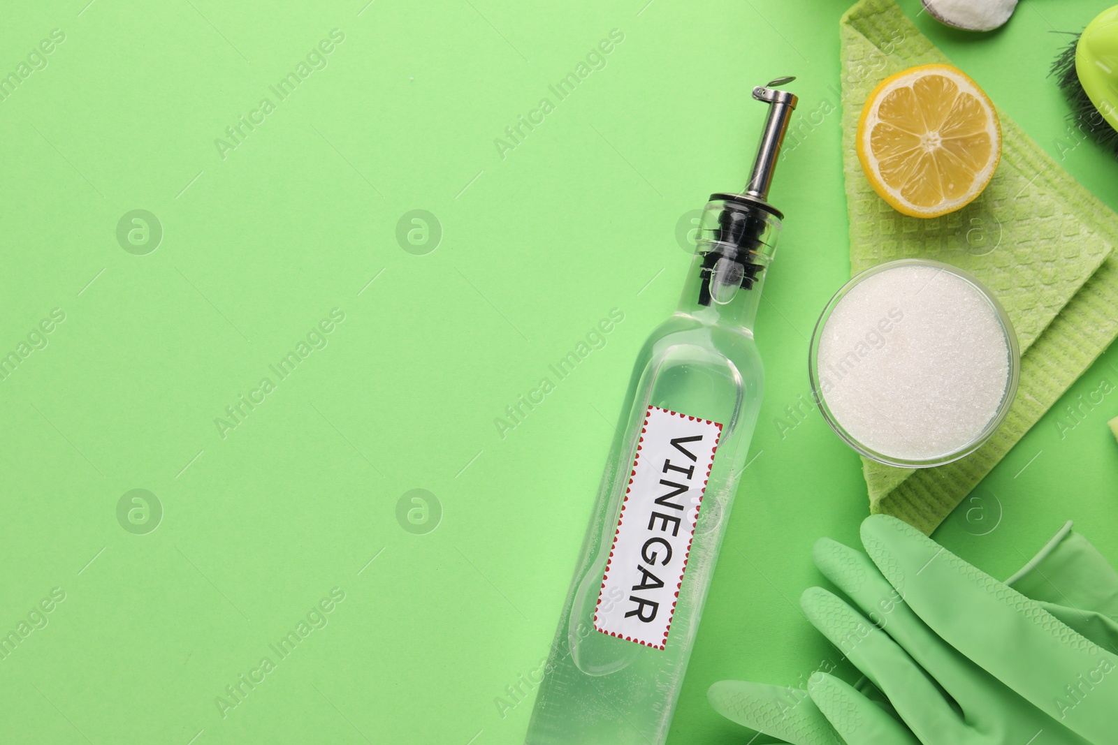 Photo of Eco friendly natural cleaners. Flat lay composition with bottle of vinegar on green background, space for text