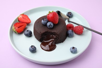 Photo of Plate with delicious chocolate fondant and berries on violet table
