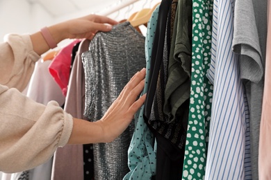 Photo of Woman choosing clothes from wardrobe rack, closeup
