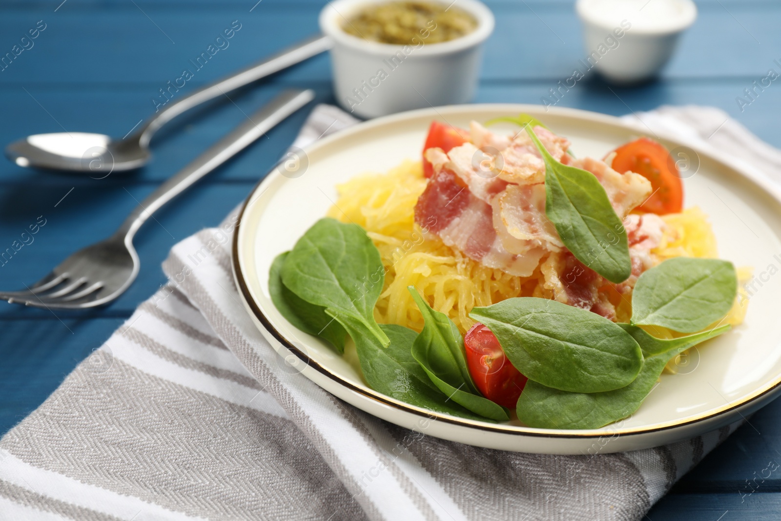 Photo of Tasty spaghetti squash with bacon and basil served on blue wooden table, closeup