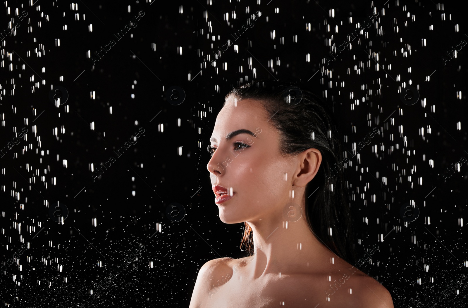 Photo of Pretty woman taking shower on black background. Washing hair