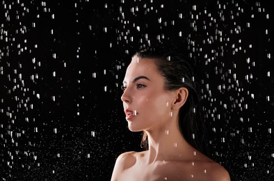 Photo of Pretty woman taking shower on black background. Washing hair