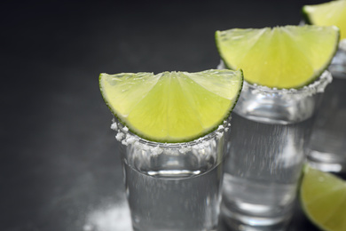 Mexican Tequila shots, lime slices and salt on table, closeup