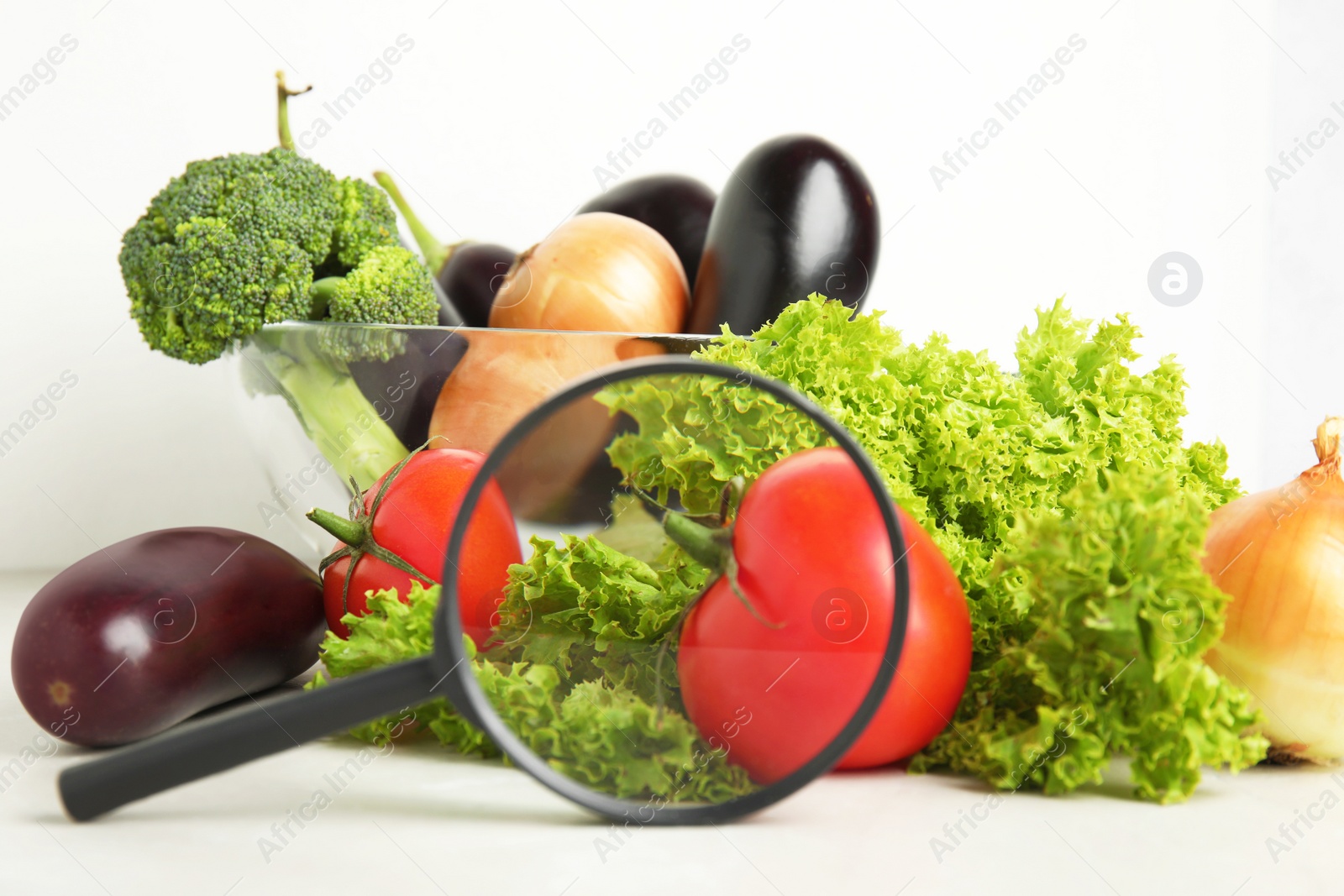 Photo of Different fresh vegetables and magnifying glass on table. Poison detection