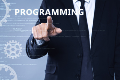 Businessman pointing at word PROGRAMMING on virtual screen, closeup 