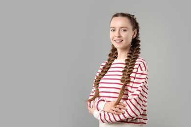 Photo of Woman with braided hair on grey background, space for text