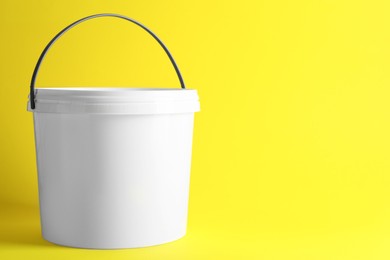 Photo of One plastic bucket with lid on yellow background. Space for text