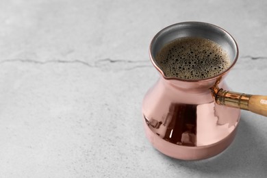 Photo of Turkish coffee in cezve on light grey table. Space for text
